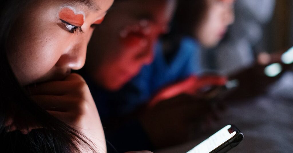 pexels-photo-5999682-5999682 Three teenagers using smartphones in bed at night, highlighting modern digital habits.