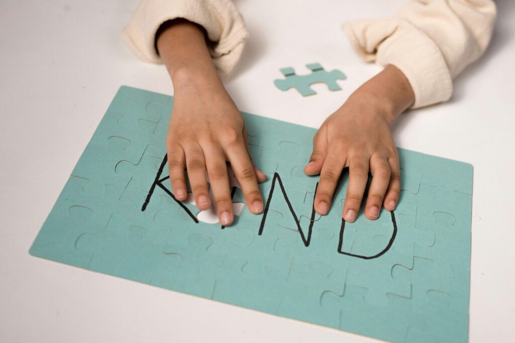 Close-up of child assembling puzzle spelling 'Kind' emphasizing kindness.